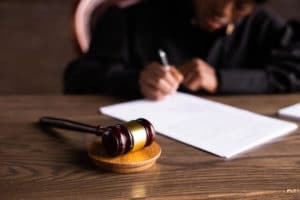 פטיש בית משפט על גבי שולחן ועורכת דין חותמת על מסמך